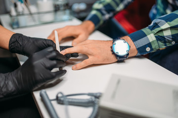 Beautician polishing nails to male client in salon