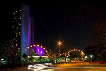 Night landscape on long exposure. Tall building and cars passing the night lights