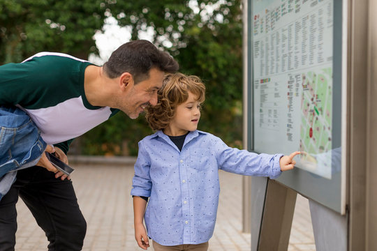 Smiling father and son looking at map in the city