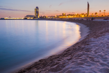 peaceful and relaxing view of barcelona beach during purple warm summer sunset with long exposure...