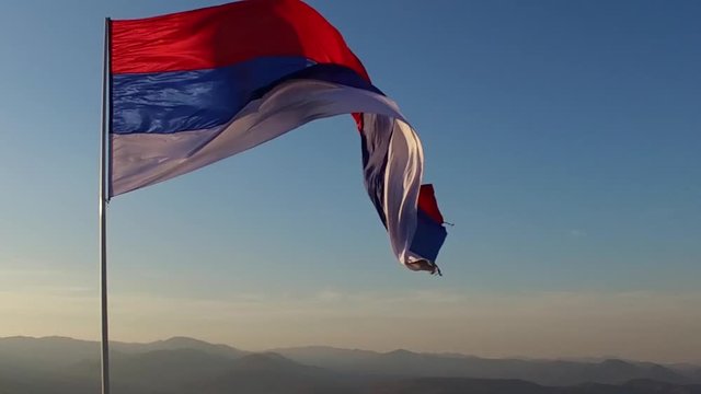 Slow Motion on Serbian Civil Flag On Top Of Zvecan Fortress in Mitrovica Kosovo With Mountains and Sky in Background