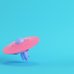 Pink ufo or alien spaceship on bright blue background in pastel colors