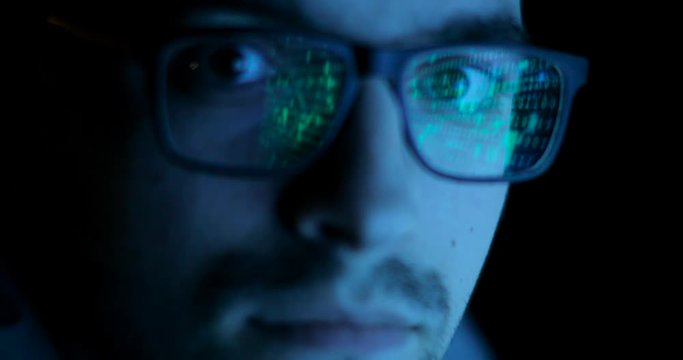 Data code reflection in programmers, hackers glasses. Man is looking at camera. Face close-up, front view.