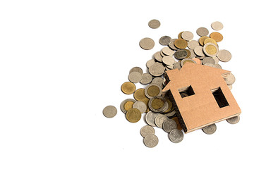 Hand holding paper home and stack of coins.