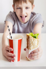 Funny Teen boy eating shawarma sandwich roll and cola