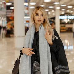 Luxurious elegant young woman blonde in a vintage warm scarf in an autumn trendy gray coat with a...