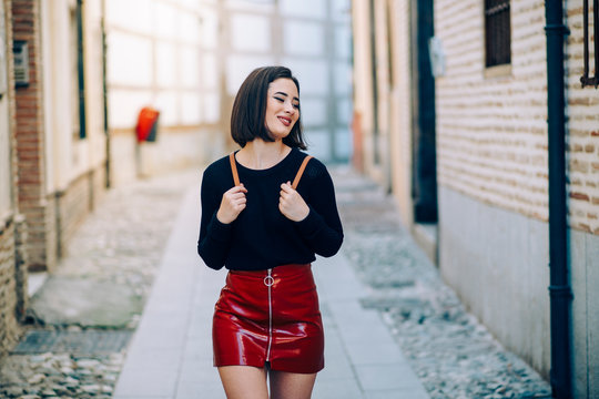 Portrait of young woman wearing red patent leather skirt with zipper