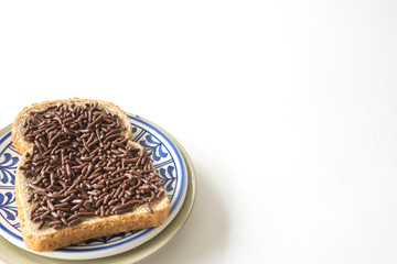 slice of bread with typical dutch chocolate hail, hagelslag . Against white background, space for text