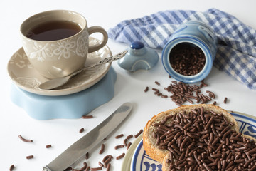slice of bread with typical dutch chocolate hail, hagelslag , cup of tea