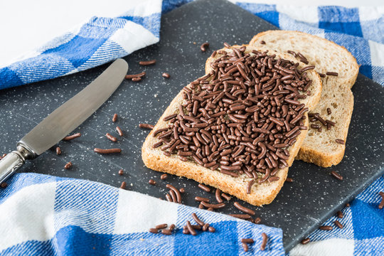 slices of wheat bread with typical dutch chocolate hail, hagelslag, on grey cutting board