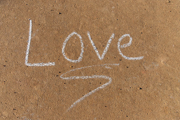 the word Love written with sidewalk chalk on gray concrete background