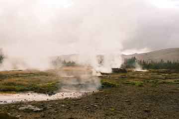 Fototapeta na wymiar stunning Iceland geyser steam and mountains in plains