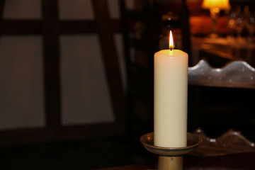 A burning paraffin candle overall on a dark background