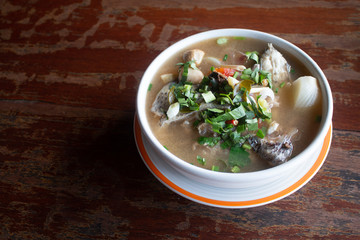 Spicy fish soup flavored with lemongrass and lime served on wooden table