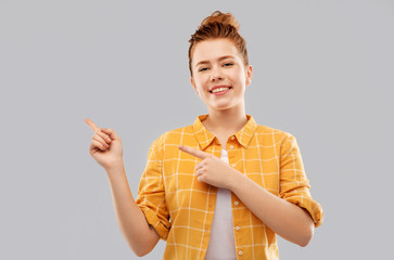 gesture, counting and people concept - smiling red haired teenage girl in checkered shirt pointing...