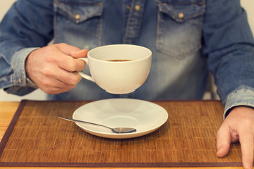 Hombre con taza de café en la cocina desayunando. Vista de frente
