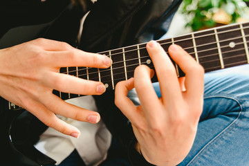Detail of the fingers of a guitarist placed on the fret of the mast of the guitar playing a chord...