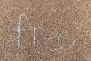 the word Free written with sidewalk chalk on gray concrete pavement background