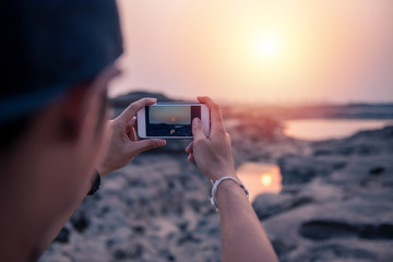 Tourist taking photo by smartphone during sunset or sunrise 