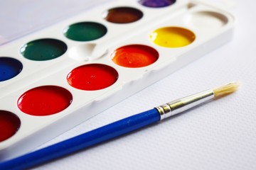 Obraz premium Watercolor paints and brushes for drawing on the table.