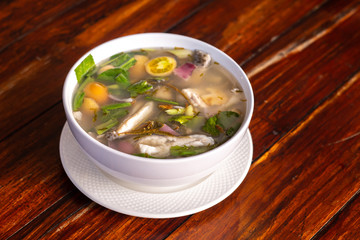 Spicy fish soup flavored with lemongrass and lime served on wooden table