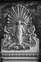 Fototapeta na wymiar Verwitterte Relief Plakette aus Stein eines weiblichen Engel an einer Mauer auf dem Dorotheenstädtischen Friedhof in Berlin