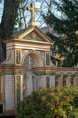 Fototapeta na wymiar Statue von Jesus Christus in einem bunt bemalten Monument aus Stein mit reichen Verzierungen auf dem Dorotheenstädtischen Friedhof in Berlin 