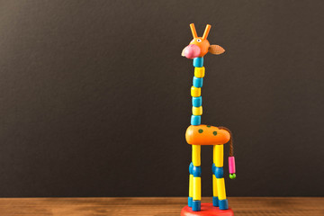 Funny toy giraffe on the wooden table. Empty text space.