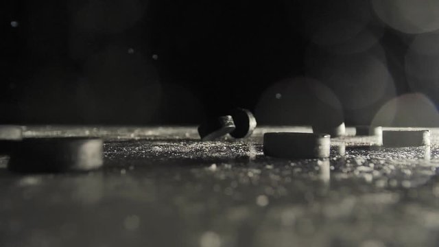 several hockey pucks fall on the ice in the dark close-up