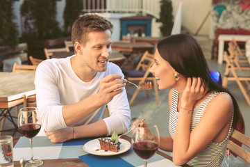 Elegant caring boyfriend feeding his long-haired girl with chocolate dessert