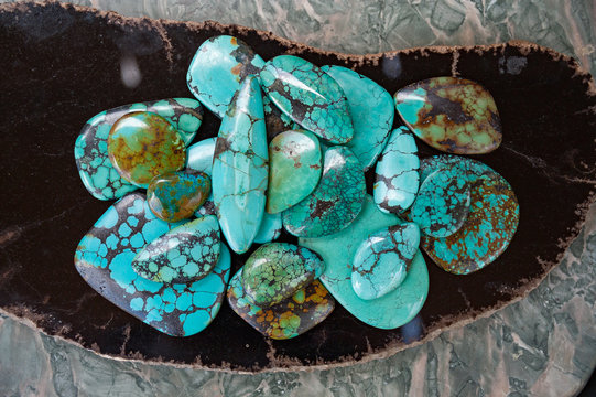 Pile of polished turquoise stones on black surface