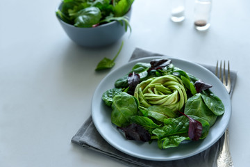 Salad mix with avocado, spinach and beet leaves on gray wooden background. Vegetarian food concept....