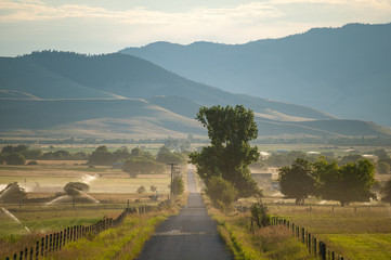 View of empty road passing through grassy landscape against mountain