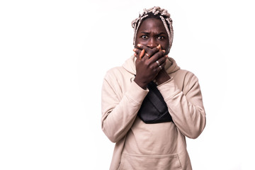 Portrait of young dark-skinned student man looking at the camera with surprised guilty expression, doing something wrong, covering his mouth. Human face expressions and emotions. Body language