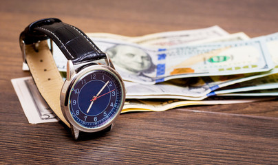 The watch is lying on dollars. Time to earn money. Time is money_