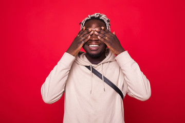 Portrait, young male, shy man closing covering eyes with hands cant see, hiding, isolated red background. See no evil concept. Negative human emotion facial expression feeling reaction