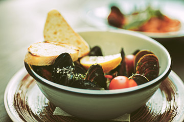 Oysters with shells served in unusual metal plate with bread and vegetables