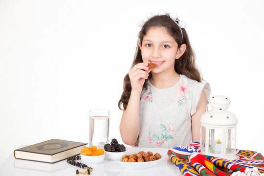 Happy young Muslim girl eating dates for iftar - breakfast in holy Ramadan
