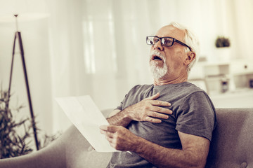 Shocked man having a heart attack after reading of papers