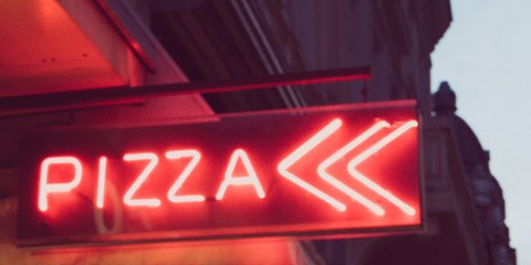 Night light red neon pizza sign in the street