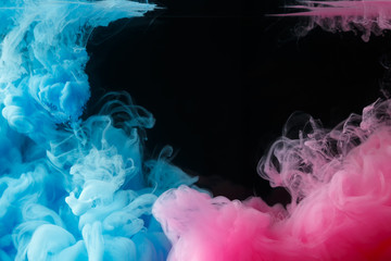 A cloud of colored acrylic paint in water. A drop of colorful ink dissolves in water on a black background. Abstract background.