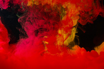 A cloud of colored acrylic paint in water. A drop of colorful ink dissolves in water on a black background. Abstract background.