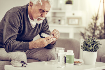 Portrait of elderly ill man holding pills box in hands