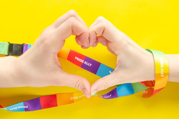 LGBT concept - two hands wrapped with a rainbow ribbon stacked together in a sign of the heart,...