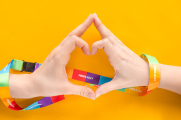 LGBT concept - two hands wrapped with a rainbow ribbon stacked together in a sign of the heart,...