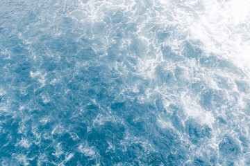 Pale blue sea surface with waves, splash,  white foam and bubbles at high tide and surf, abstract background