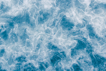 Pale blue sea surface with waves, splash,  white foam and bubbles at high tide and surf, abstract background