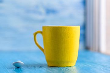 Yellow mug on a wooden background photographed close-up.