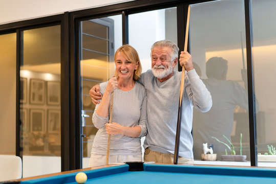 Lovers In A Living Room. Happy Senior Couple Playing Billiards On Vacation Together In Home.Lifestyle Senior Concept.