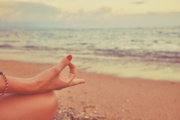Young woman practicing yoga on the beach.